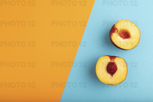 Peach Cut in half on orange and blue paper pastel background. Top view, flat lay, copy space.