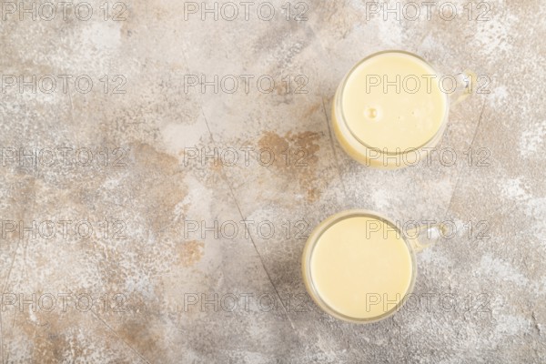 Organic non dairy banana and soy milk in glass on brown concrete background. Vegan healthy food