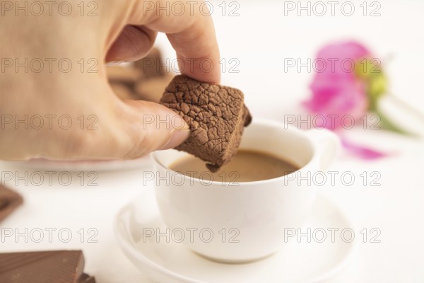 Chocolate marshmallow with cup of coffee with hand on white wooden background. side view, close up,