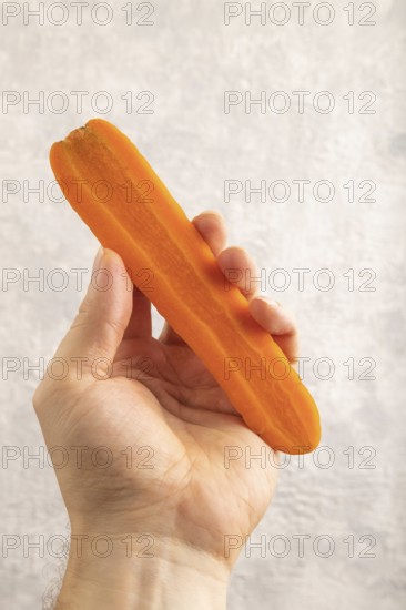 Orange Carrot with hand on gray concrete background. Top view, close up, flat lay. healthy food,