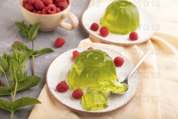 Mint and raspberry green jelly on gray concrete background and orange linen textile. side view,