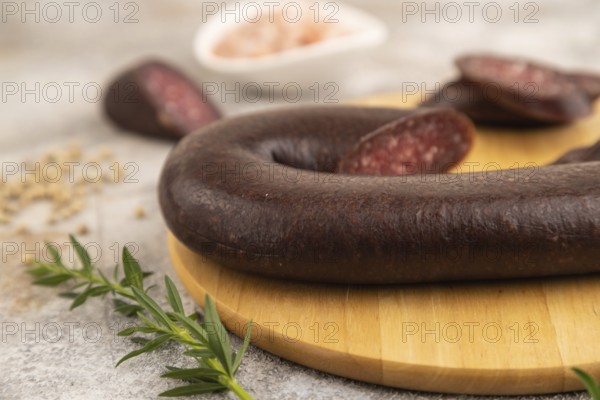 Sujuk sausage on wooden cutting board with pepper and herbs on brown concrete background. Side