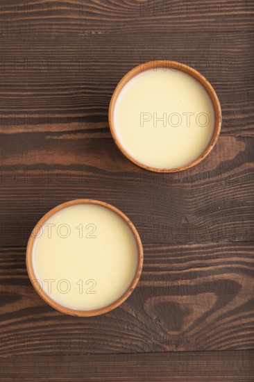 Organic non dairy banana and soy milk in clay cup on brown wooden background. Vegan healthy food
