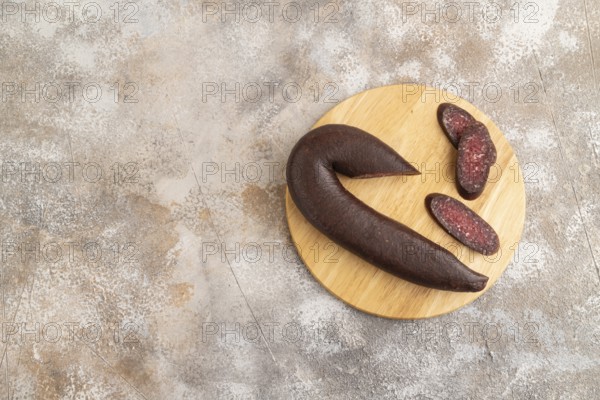 Sujuk sausage on wooden cutting board with pepper and herbs on brown concrete background. Top view,