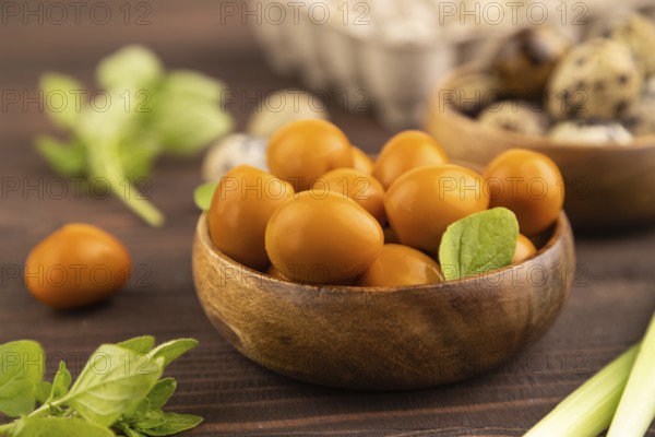 Pile of Smoked Quail eggs in bowl on a brown wooden background. side view, close up, selective