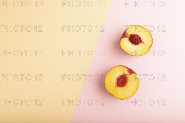 Peach Cut in half on orange and pink paper pastel background. Top view, flat lay, copy space.