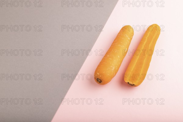 Orange Carrot on gray and pink pastel paper background. Side view, copy space, flat lay. healthy