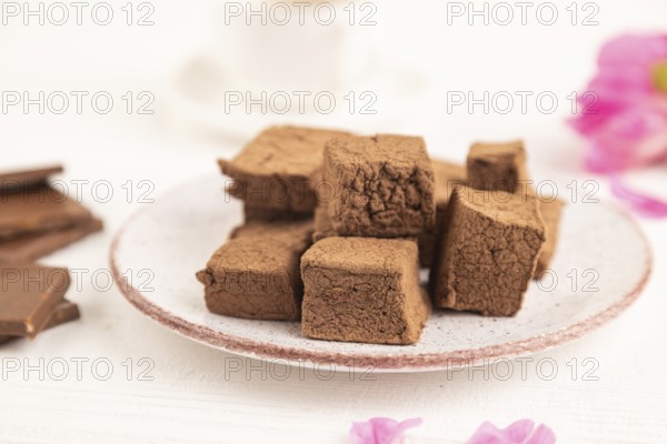 Chocolate marshmallow with cup of coffee on white wooden background. side view, close up, selective