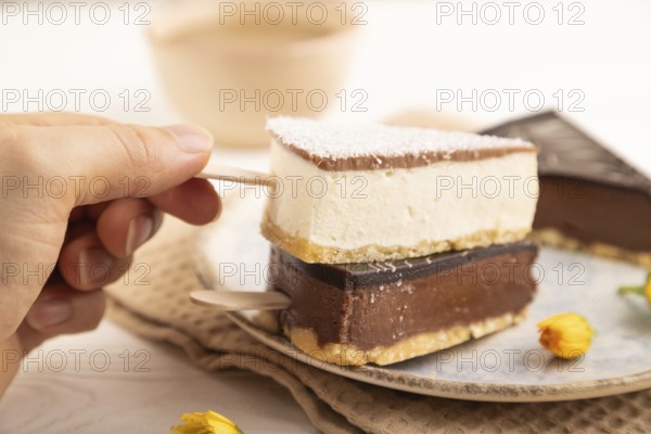 Chocolate and Vanilla Cake pops Marshmallow with hand with cup of coffee on white wooden background