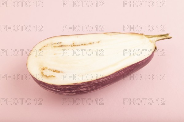 Purple Cutted eggplant with white stripes on pink pastel background. Side view, copy space.
