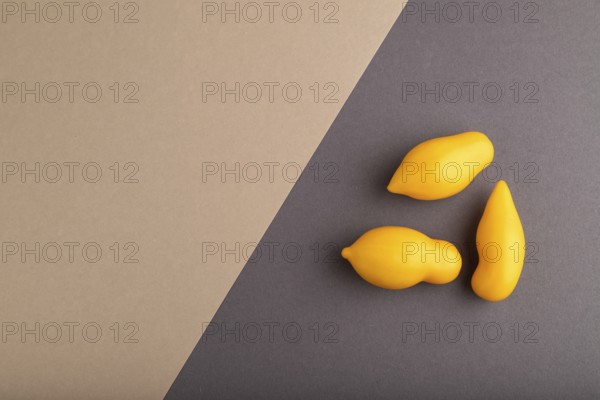 Yellow tomatoes on beige and gray pastel paper background. Top view, copy space, flat lay. healthy