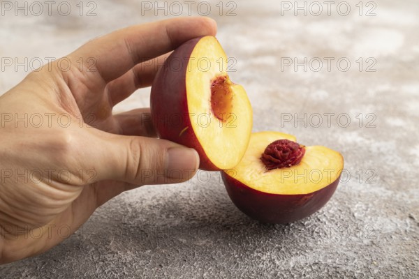 Peach Cut in half with hand on brown concrete background. Side view, copy space. healthy food,