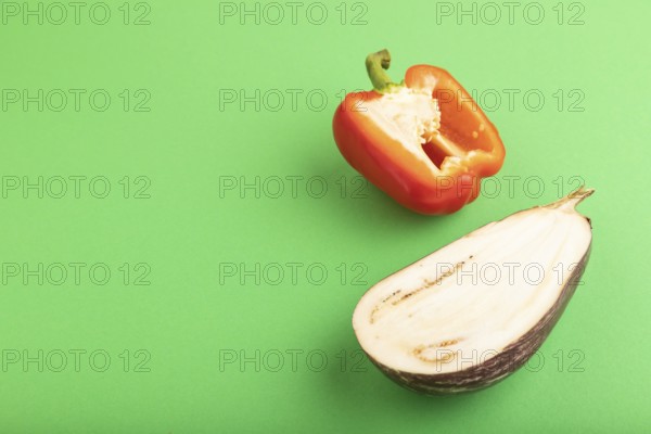 Red Cutted pepper and Purple Cutted eggplant on green pastel background. Side view, copy space.