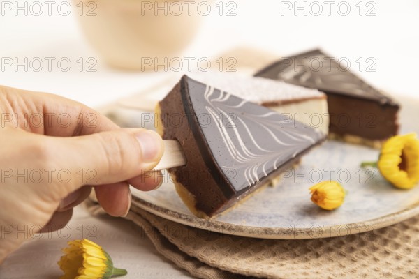 Chocolate and Vanilla Cake pops Marshmallow with hand with cup of coffee on white wooden background