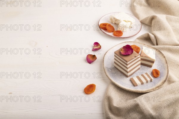 Cocoa and milk jelly with dried apricots on white wooden background and linen textile, side view,