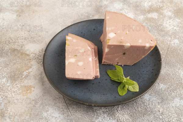 Mortadella sausage on wooden cutting board with pepper and herbs on brown concrete background. Side