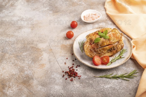 Fried Turkey Thigh with spices and rosemary on plate on brown concrete background and orange linen