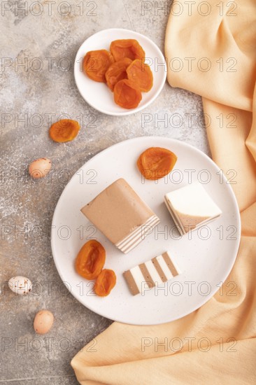 Cocoa and milk jelly with dried apricots on brown concrete background and orange textile, top view,