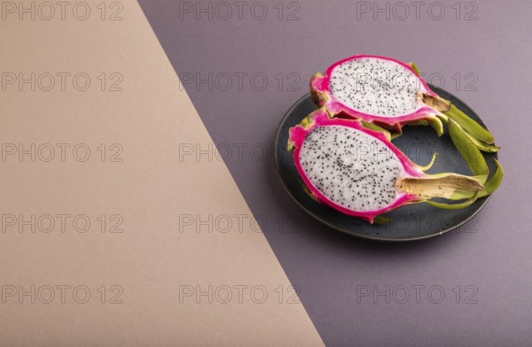Ripe Pitaya on blue plate on brown and beige pastel paper background, side view, copy space,