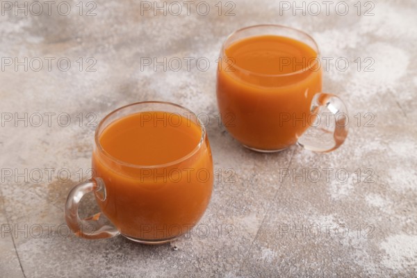 Two glasses with carrot juice, on brown concrete background. Diet, healthy eating concept. side