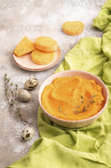 Sweet potato porridge in ceramic bowl on brown concrete background and green textile. Diet, healthy