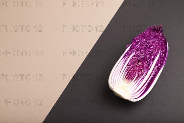 Purple Chinese cabbage on brown and black pastel paper background, side view, copy space,