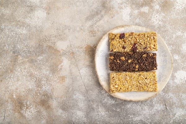 Granola bars with caramel, nuts, flakes in ceramic plate on brown concrete background. Top view,