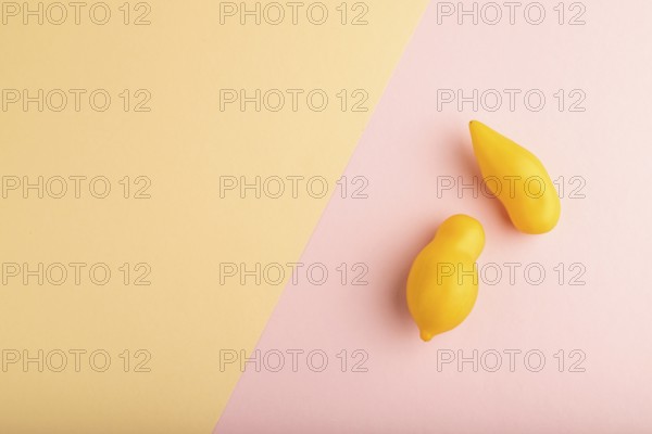 Yellow tomatoes on pink and orange pastel paper background. Top view, copy space, flat lay. healthy