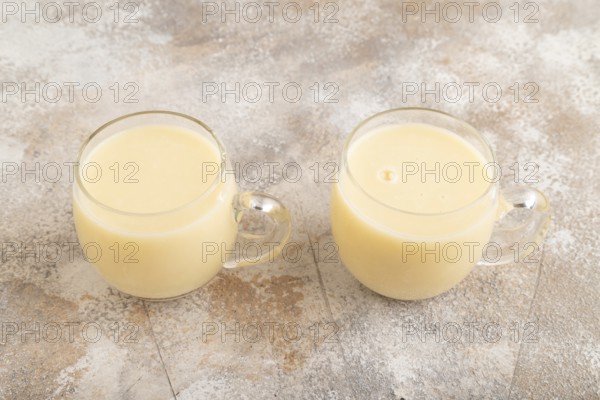 Organic non dairy banana and soy milk in glass on brown concrete background. Vegan healthy food