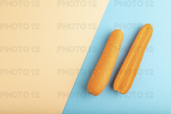Orange Carrot on orange and blue pastel paper background. Top view, copy space, flat lay. healthy