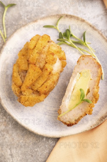 Chicken Schnitzel on blue plate with microgreen on brown concrete background and orange linen