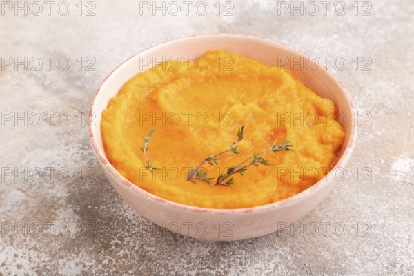 Sweet potato porridge in ceramic bowl on brown concrete background. Diet, healthy eating concept.