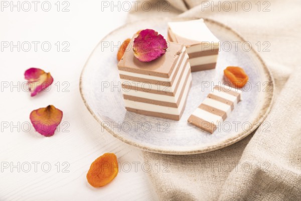 Cocoa and milk jelly with dried apricots on white wooden background and linen textile, side view,