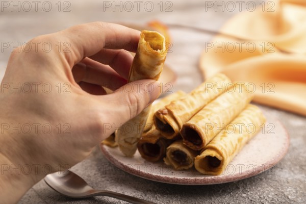Waffles with caramel with hand on brown concrete background and orange linen textile, side view,