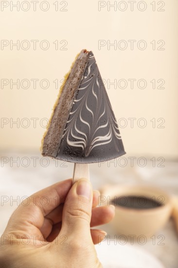 Chocolate and Vanilla Cake pops Marshmallow with hand with cup of coffee on brown concrete