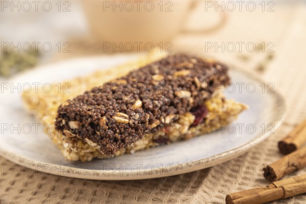 Granola bars with caramel, nuts, flakes in ceramic plate on brown concrete background, beige linen