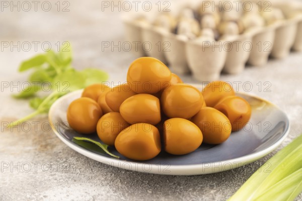 Pile of Smoked Quail eggs on plate on a brown concrete background. side view, close up, selective