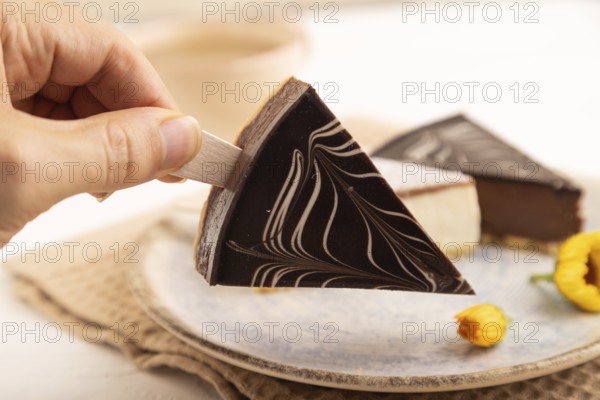 Chocolate and Vanilla Cake pops Marshmallow with hand with cup of coffee on white wooden background