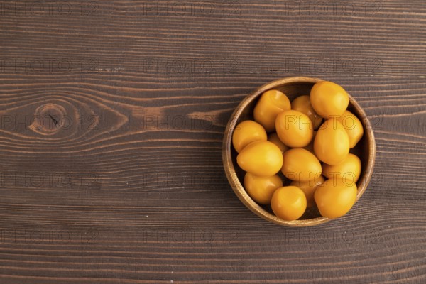 Pile of Smoked Quail eggs in bowl on a brown wooden background. top view, flat lay, copy space