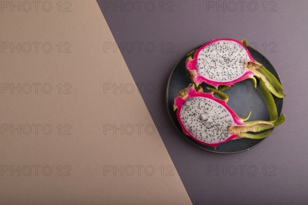 Ripe Pitaya on blue plate on brown and beige pastel paper background, top view, flat lay, copy