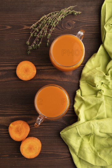 Two glasses with carrot juice, on wooden background and green textile. Diet, healthy eating concept