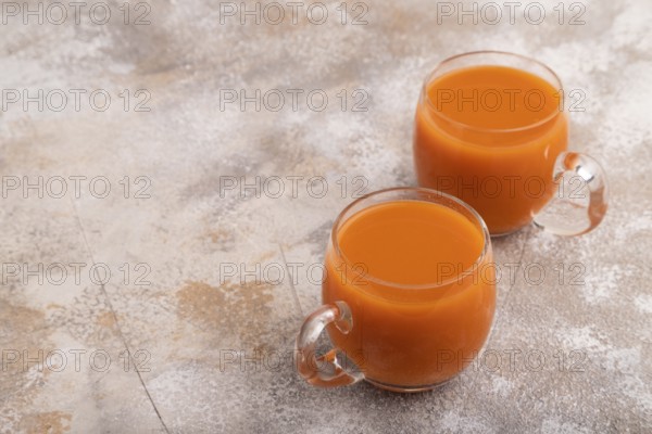 Two glasses with carrot juice, on brown concrete background. Diet, healthy eating concept. side
