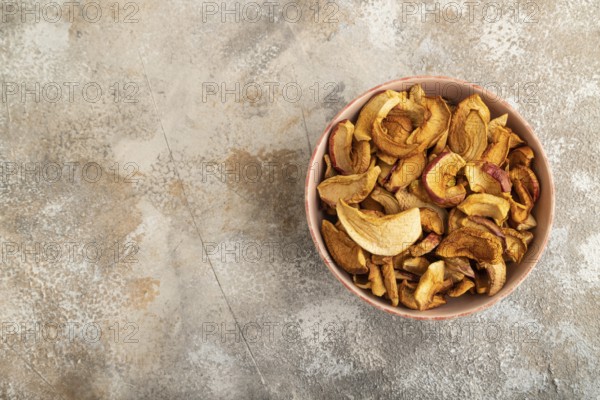 Dried Apples in ceramic bowl on brown concrete background. Top view, copy space, flat lay. healthy