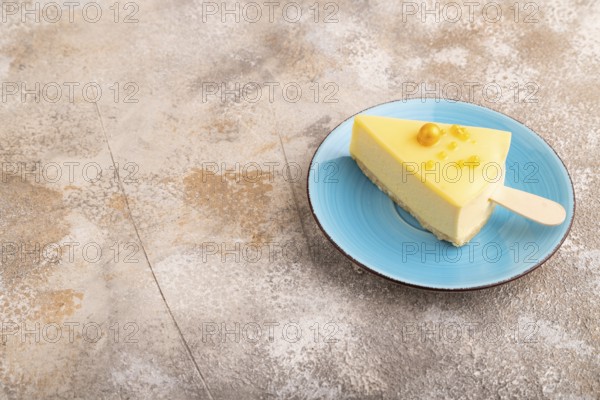 Yellow Cake pop with sprinkles on blue ceramic plate on brown concrete background, side view, copy