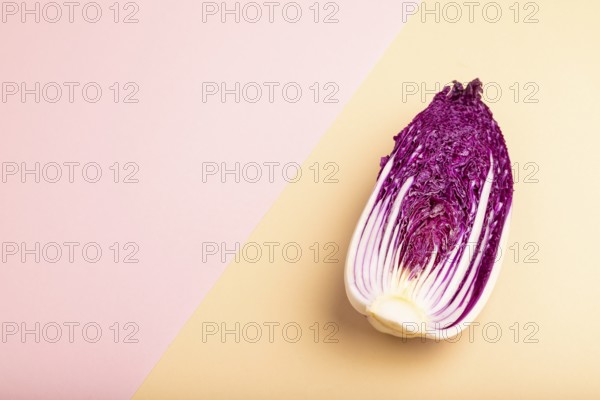 Purple Chinese cabbage on pink and orange pastel paper background, side view, copy space,