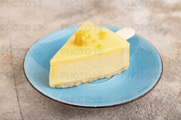 Yellow Cake pop with sprinkles on blue ceramic plate on brown concrete background, side view, close
