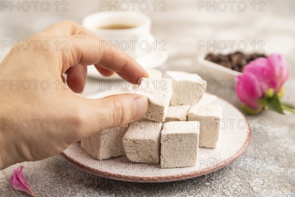 Coffee marshmallow with cup of coffee with hand on brown concrete background. side view, close up,