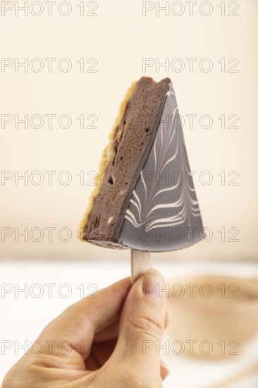 Chocolate and Vanilla Cake pops Marshmallow with hand with cup of coffee on white wooden background