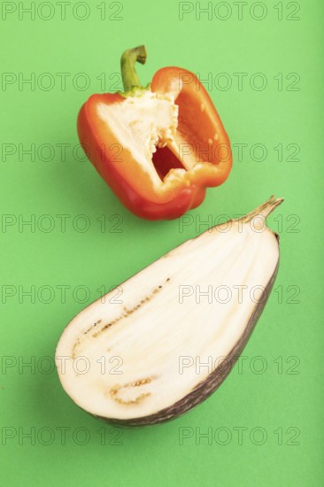 Red Cutted pepper and Purple Cutted eggplant on green pastel background. Side view, copy space.