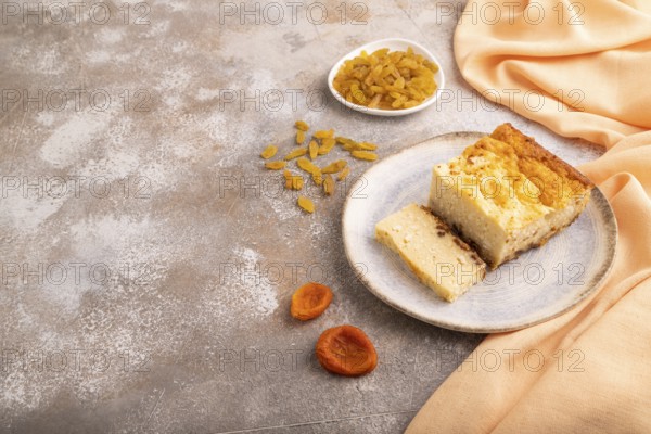 ?ottage cheese ?asserole, Curd cake, with dried apricots and raisins on brown concrete background